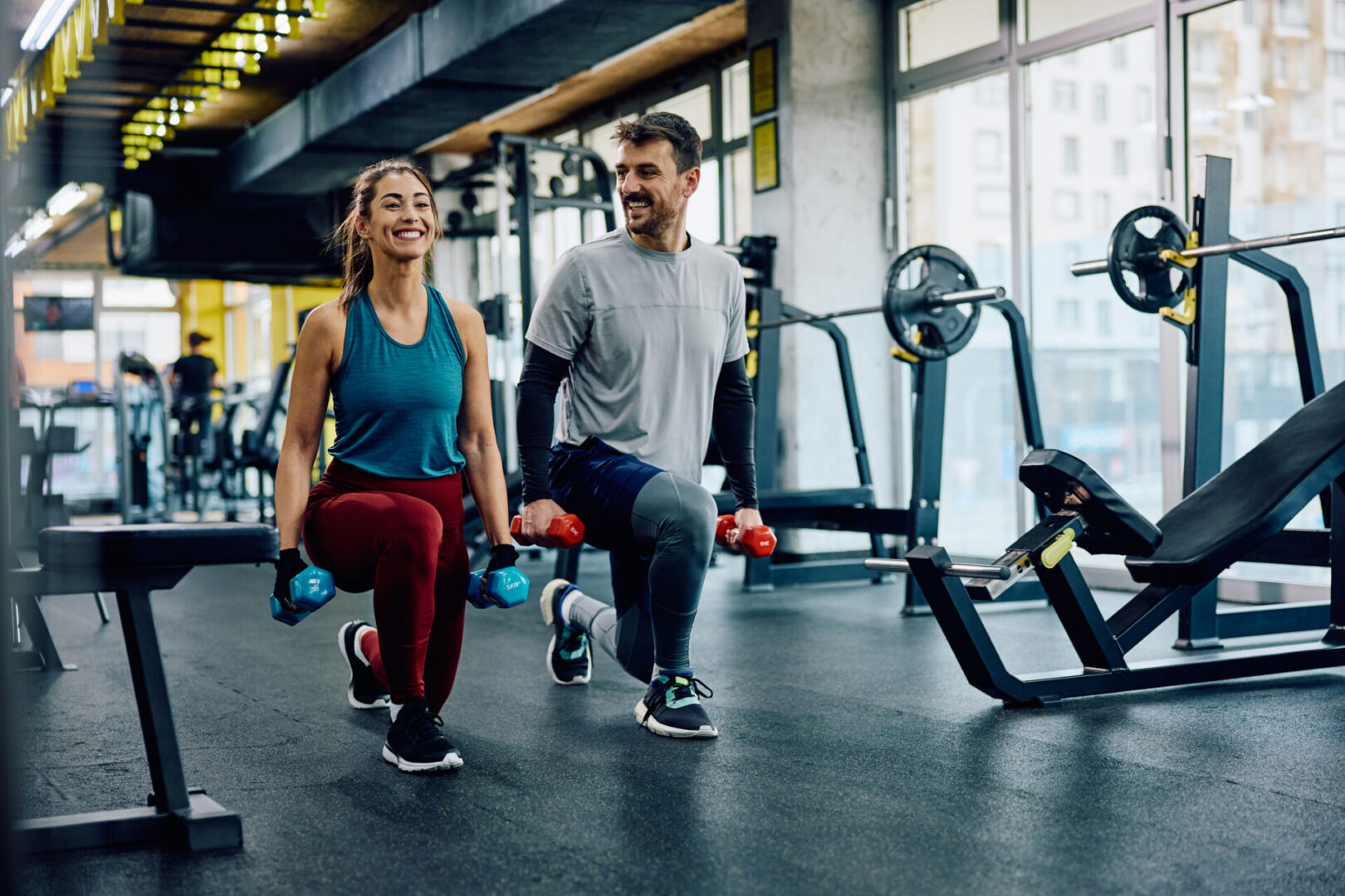 Couple weight training lunges at gym.