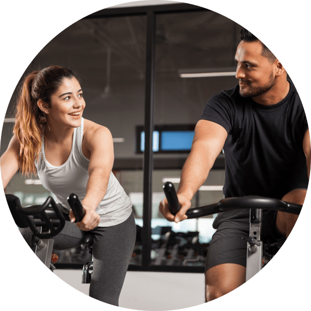 Couple on stationary bikes at the gym.